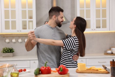 Happy lovely couple dancing together while cooking in kitchen