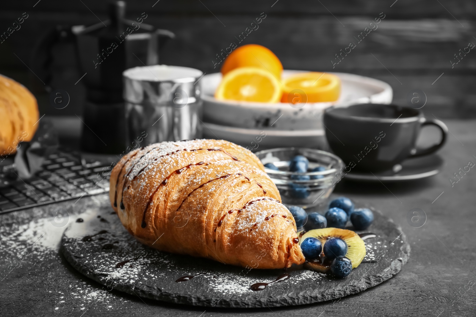 Photo of Tasty croissant with sugar powder on slate plate