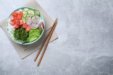 Photo of Delicious poke bowl with salmon, seaweed and vegetables served on light grey table, flat lay. Space for text
