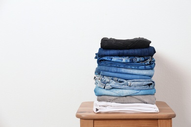 Photo of Stack of different jeans on table against white background. Space for text