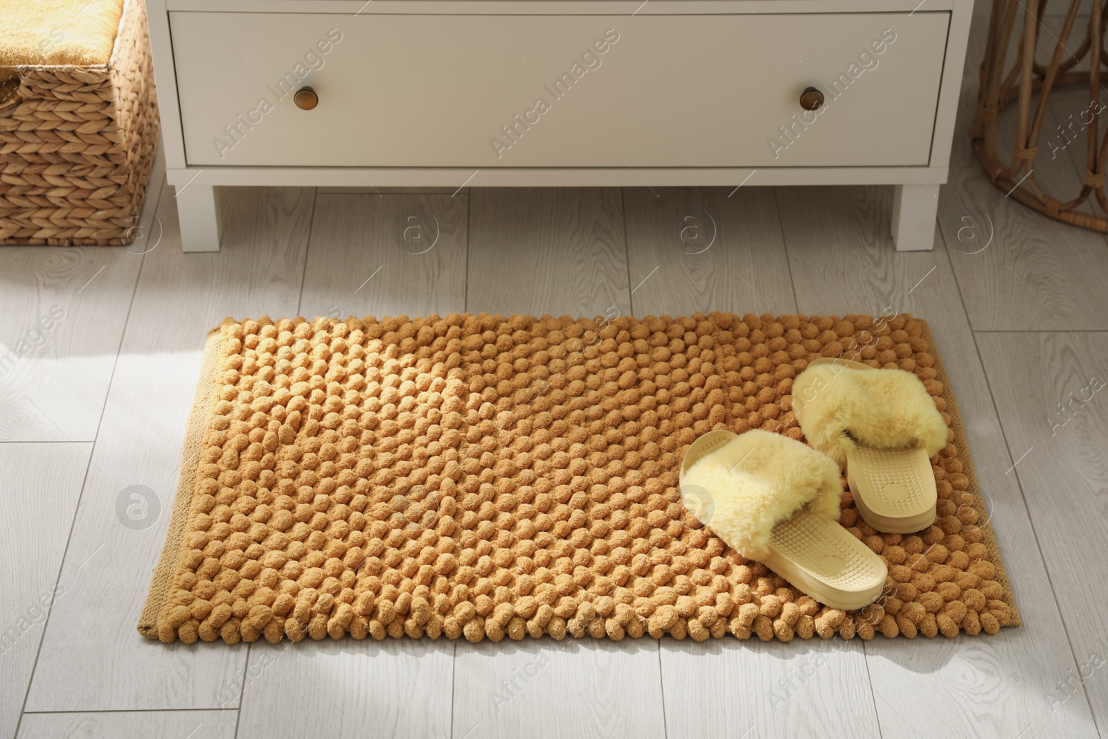 Photo of Stylish orange mat with slippers near chest of drawers in bathroom