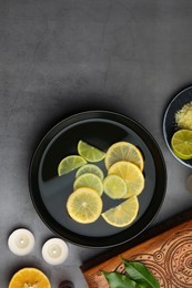 Photo of Flat lay composition with essential oil and lemons on grey table, space for text. Aromatherapy treatment