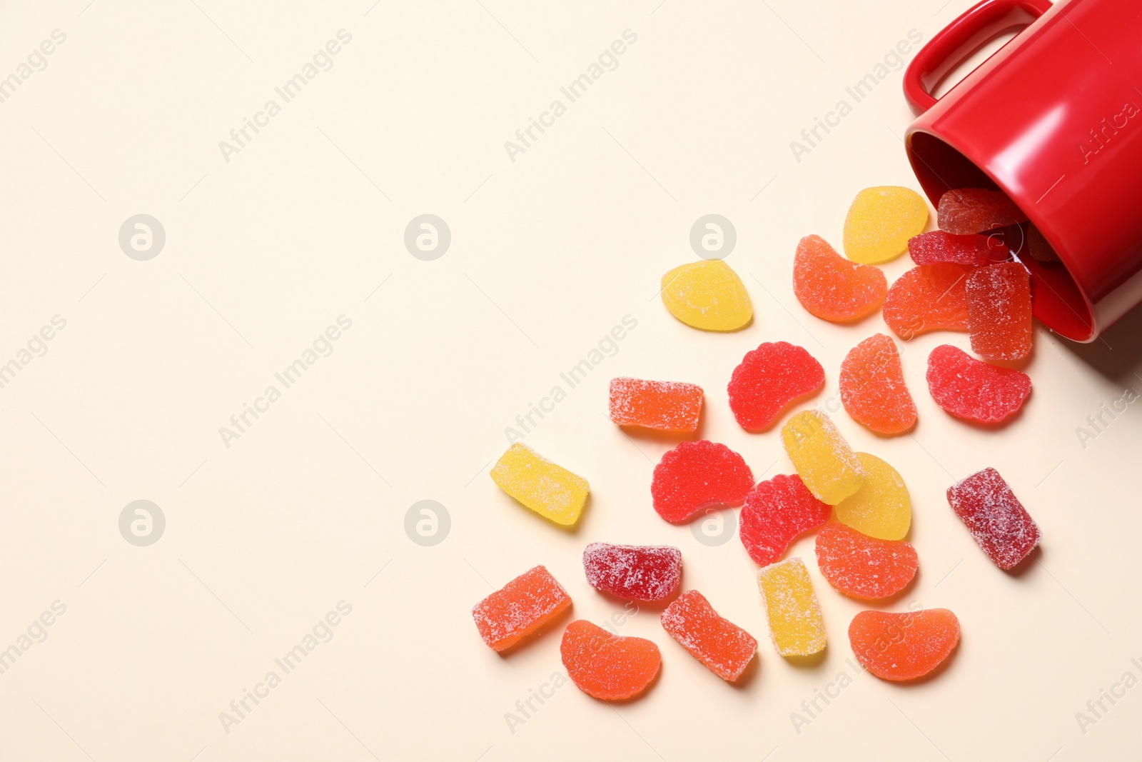 Photo of Tasty jelly candies and cup on light background, above view. Space for text