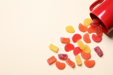 Tasty jelly candies and cup on light background, above view. Space for text