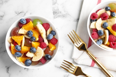 Photo of Fresh tasty fruit salad on white marble table, flat lay