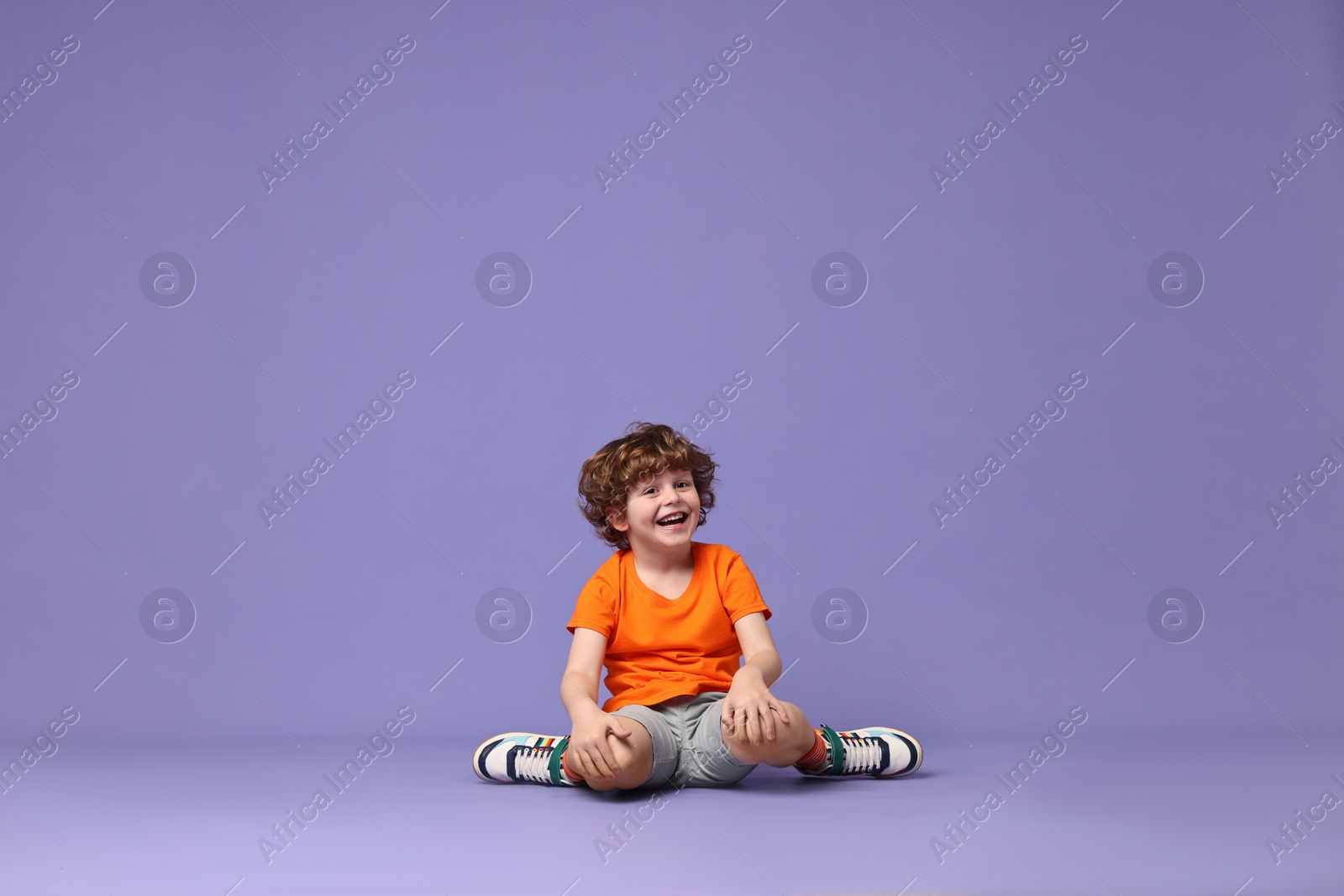 Photo of Happy little boy dancing on violet background. Space for text