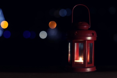 Photo of Lantern on wooden railing outdoors against blurred background, space for text. Winter night