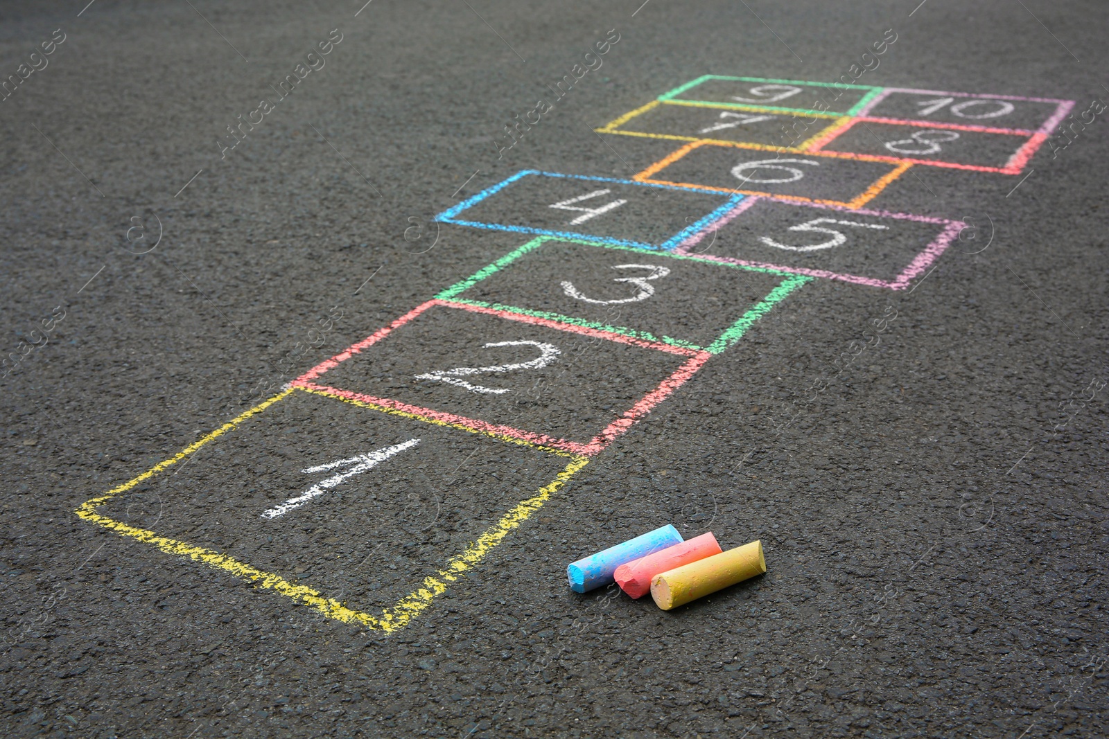 Photo of Hopscotch drawn with colorful chalk on asphalt outdoors, closeup