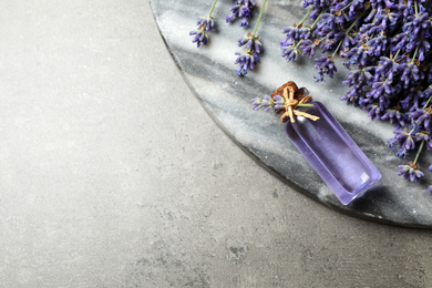 Photo of Flat lay composition with lavender flowers and essential oil on grey background. Space for text