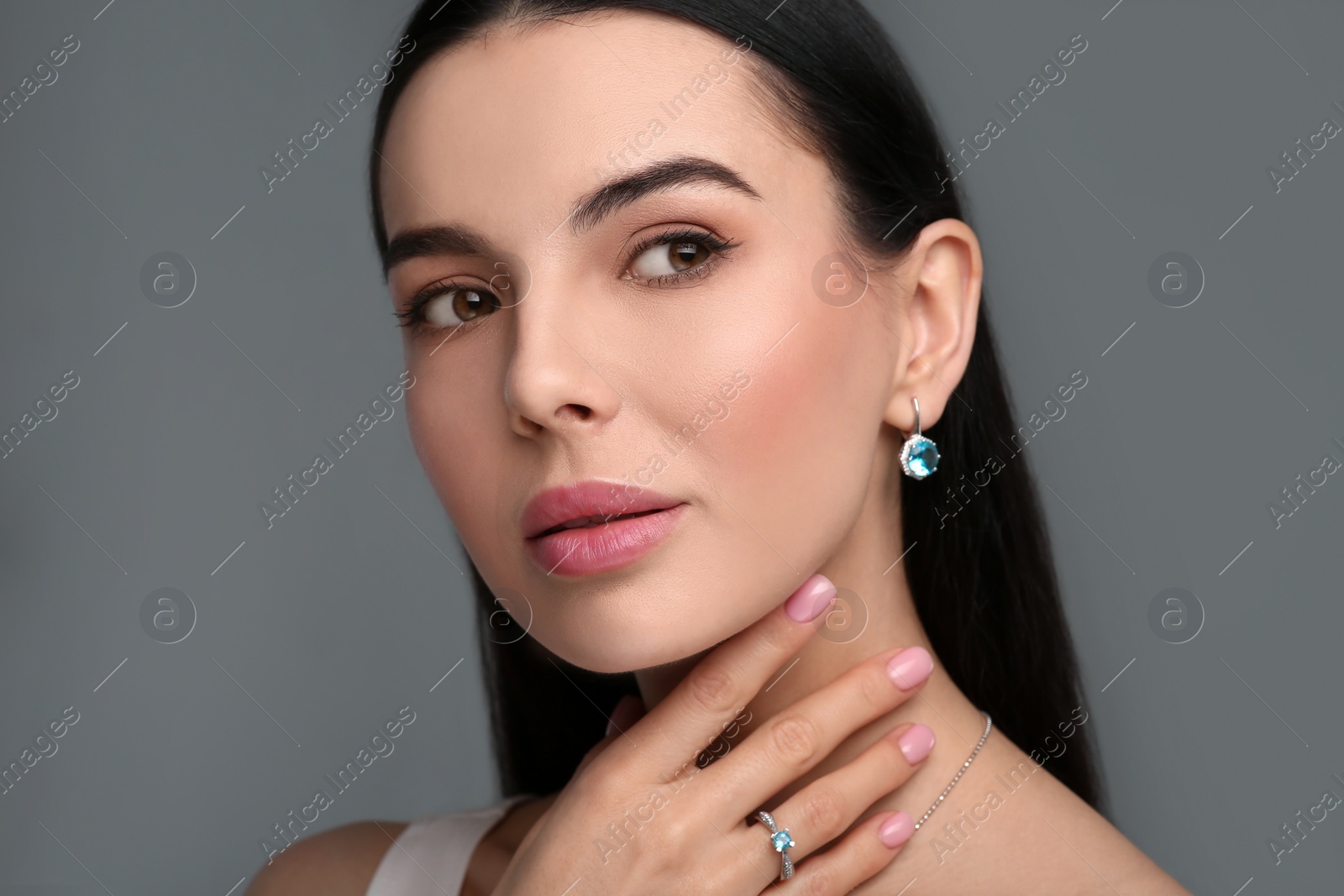 Photo of Beautiful young woman with elegant jewelry on dark grey background, closeup
