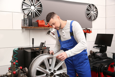 Mechanic working with car disk lathe machine at tire service