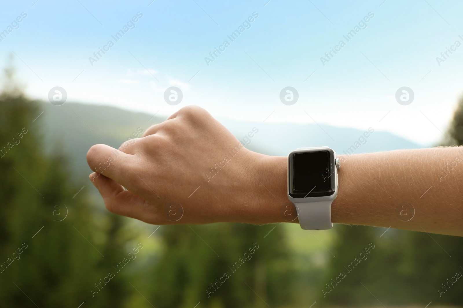 Photo of Woman checking smart watch with blank screen in wilderness, closeup