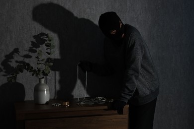 Photo of Thief stealing jewels in foreign house. Burglary