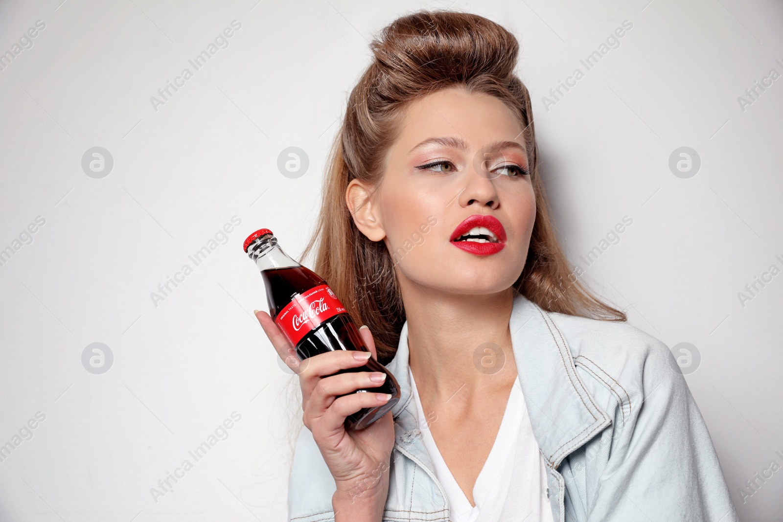 Photo of MYKOLAIV, UKRAINE - NOVEMBER 28, 2018: Young woman with bottle of Coca-Cola on white background