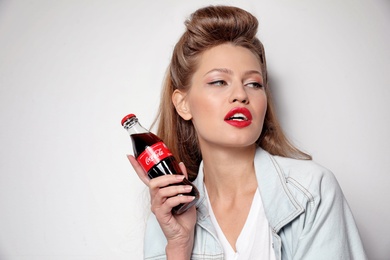 Photo of MYKOLAIV, UKRAINE - NOVEMBER 28, 2018: Young woman with bottle of Coca-Cola on white background