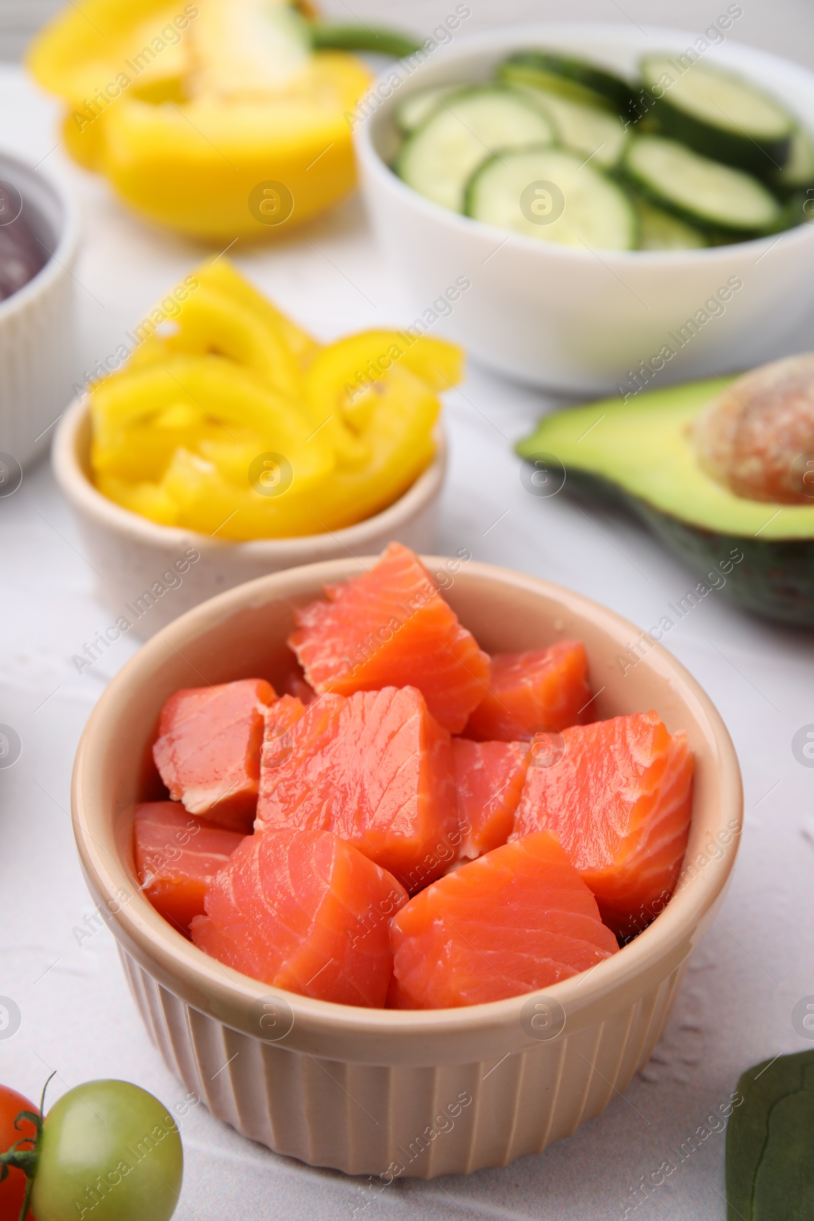 Photo of Ingredients for poke bowl on white textured table, closeup