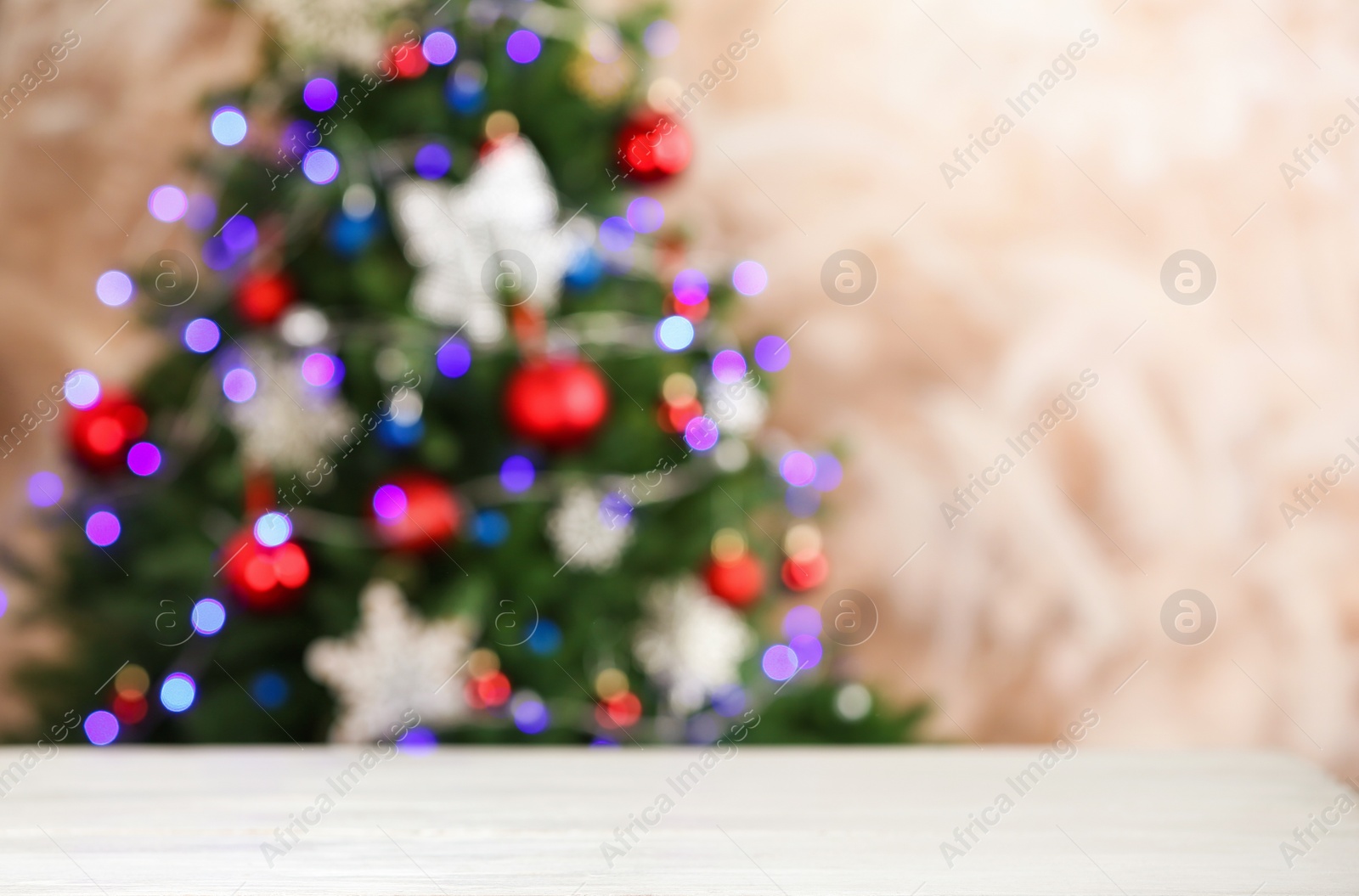 Photo of Empty white wooden table and blurred fir tree with Christmas lights on background, bokeh effect. Space for design