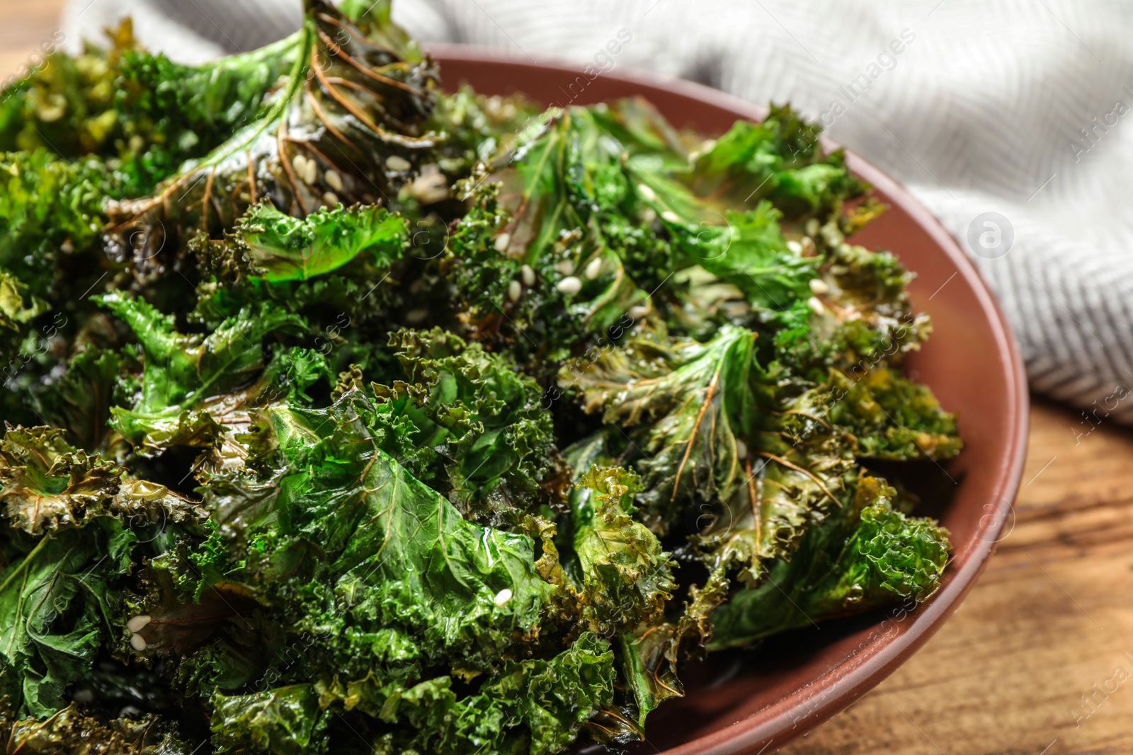 Photo of Tasty baked kale chips on wooden table, closeup