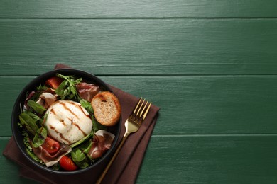 Delicious burrata salad served on green wooden table, top view. Space for text