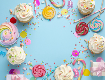 Photo of Flat lay composition with cupcakes on light blue background, space for text. Birthday party