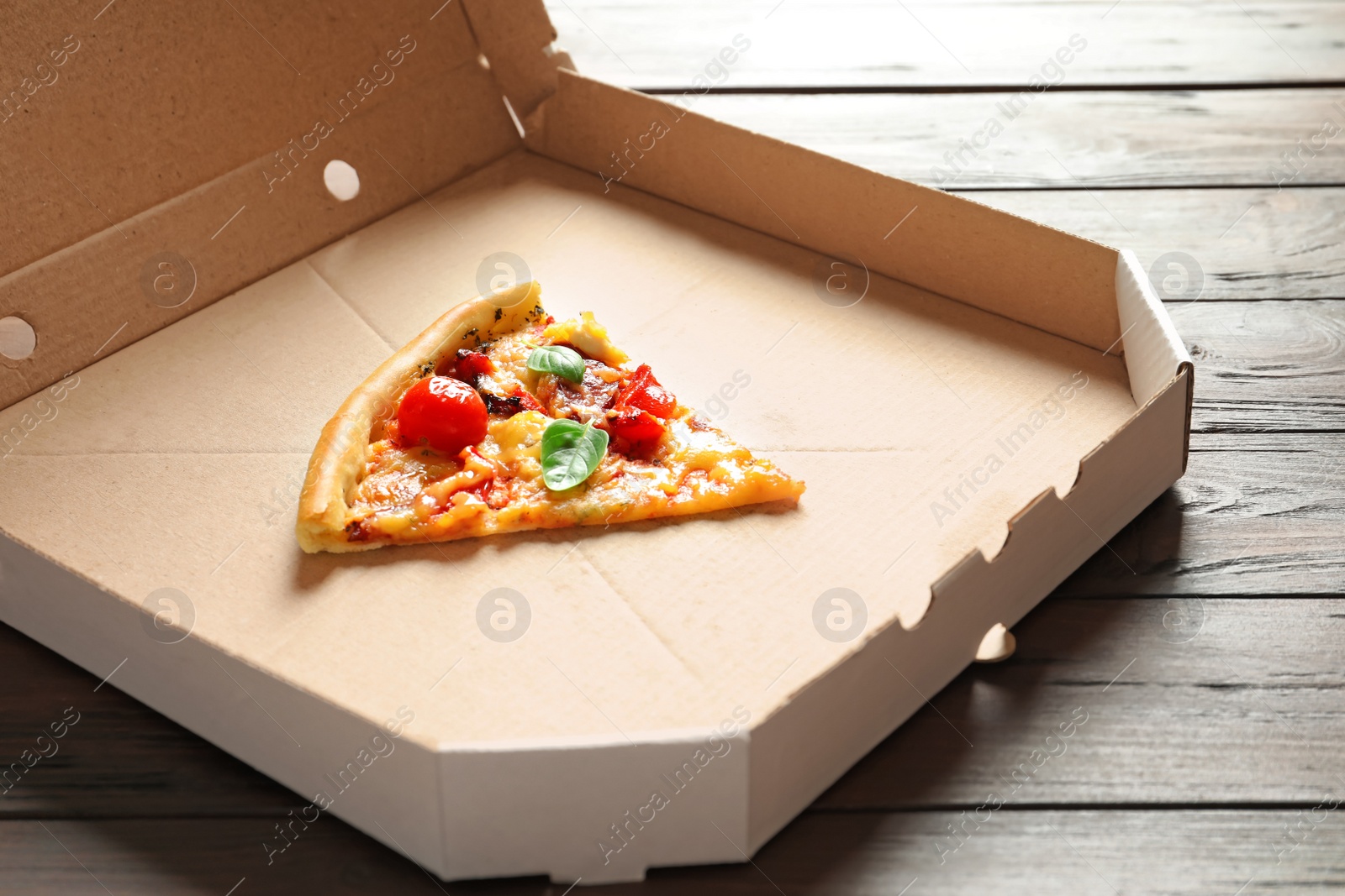 Photo of Last slice of tasty pizza in cardboard box on table