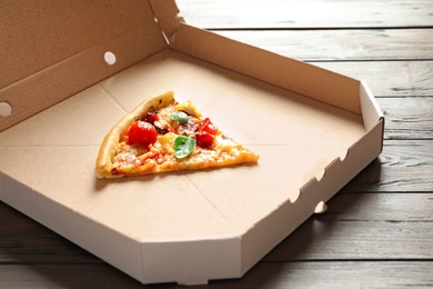 Last slice of tasty pizza in cardboard box on table