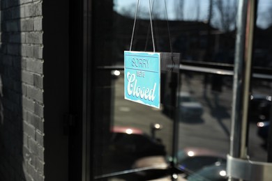 Photo of Light blue sign with text Sorry we're Closed hanging on glass door. Coronavirus quarantine