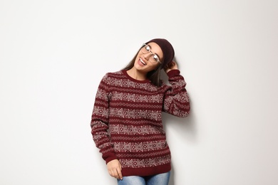 Young woman in warm sweater and hat on white background. Celebrating Christmas