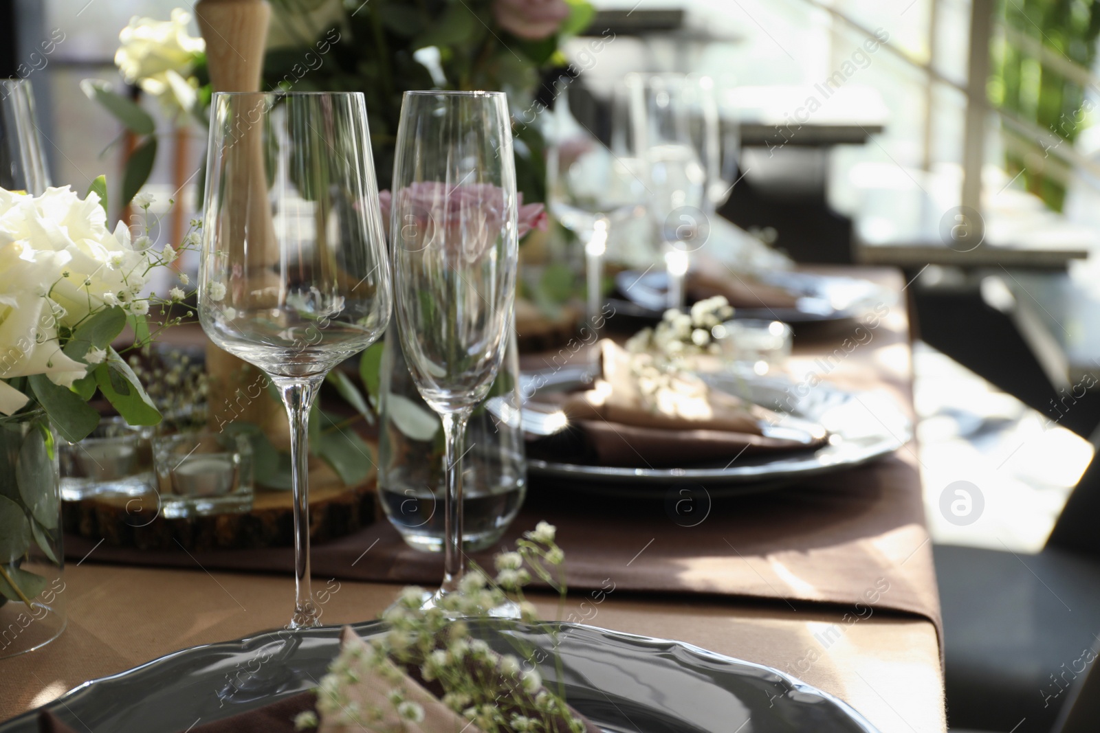 Photo of Festive table setting with beautiful tableware and floral decor in restaurant