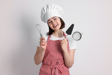 Photo of Happy confectioner holding professional tools on light grey background