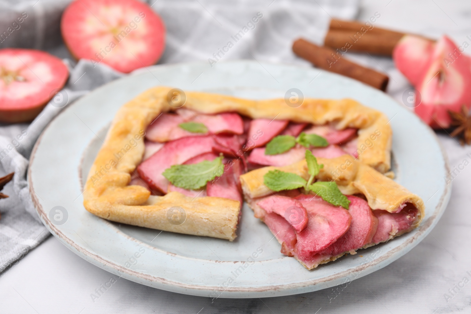 Photo of Delicious apple galette with mint on white marble table, closeup