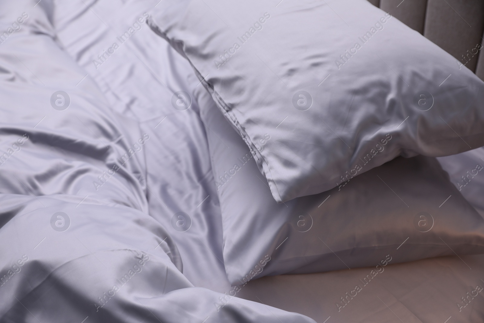 Photo of Cozy bed with soft silky bedclothes, closeup