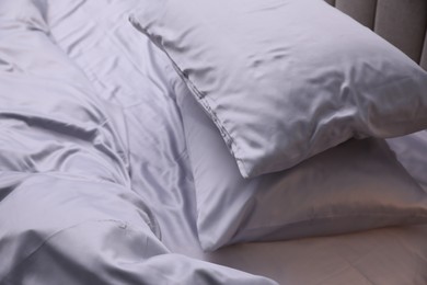 Photo of Cozy bed with soft silky bedclothes, closeup