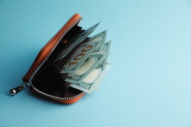 Photo of One open purse with money on light blue background. Space for text