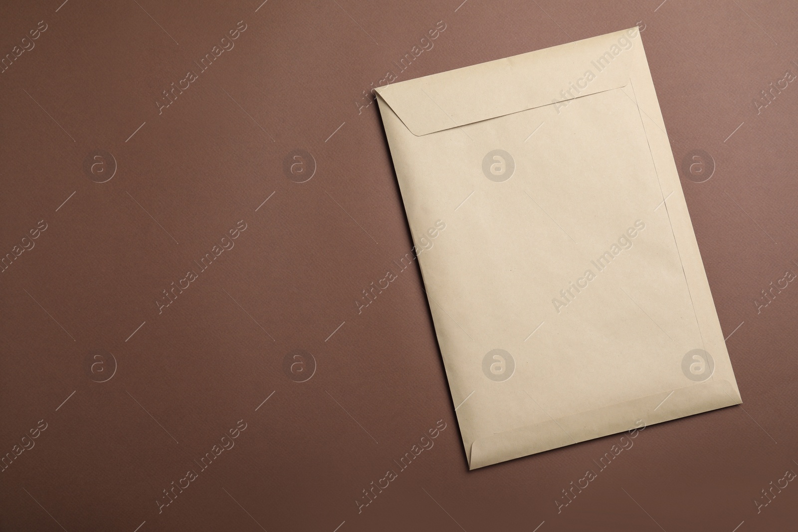 Photo of Kraft paper envelope on brown background, top view. Space for text