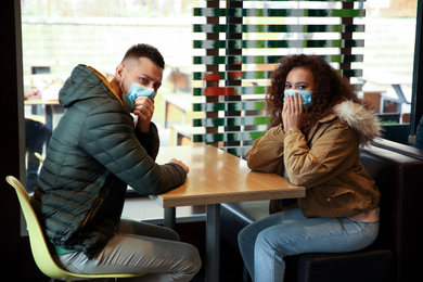 Couple with disposable masks in cafe. Virus protection