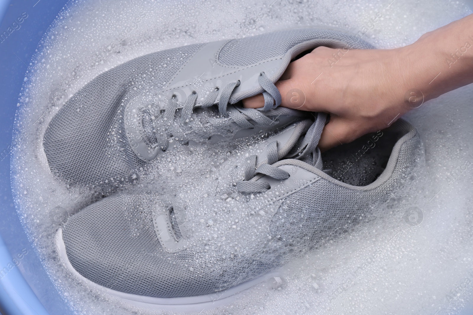 Photo of Woman washing sport shoes in plastic basin, top view