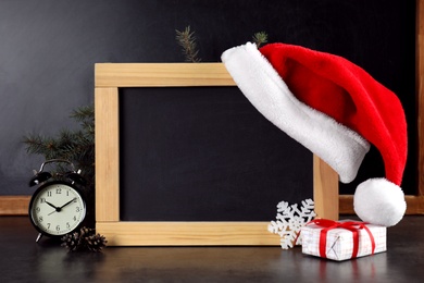 Photo of Christmas composition with blank blackboard and decor on table, space for text. School holidays