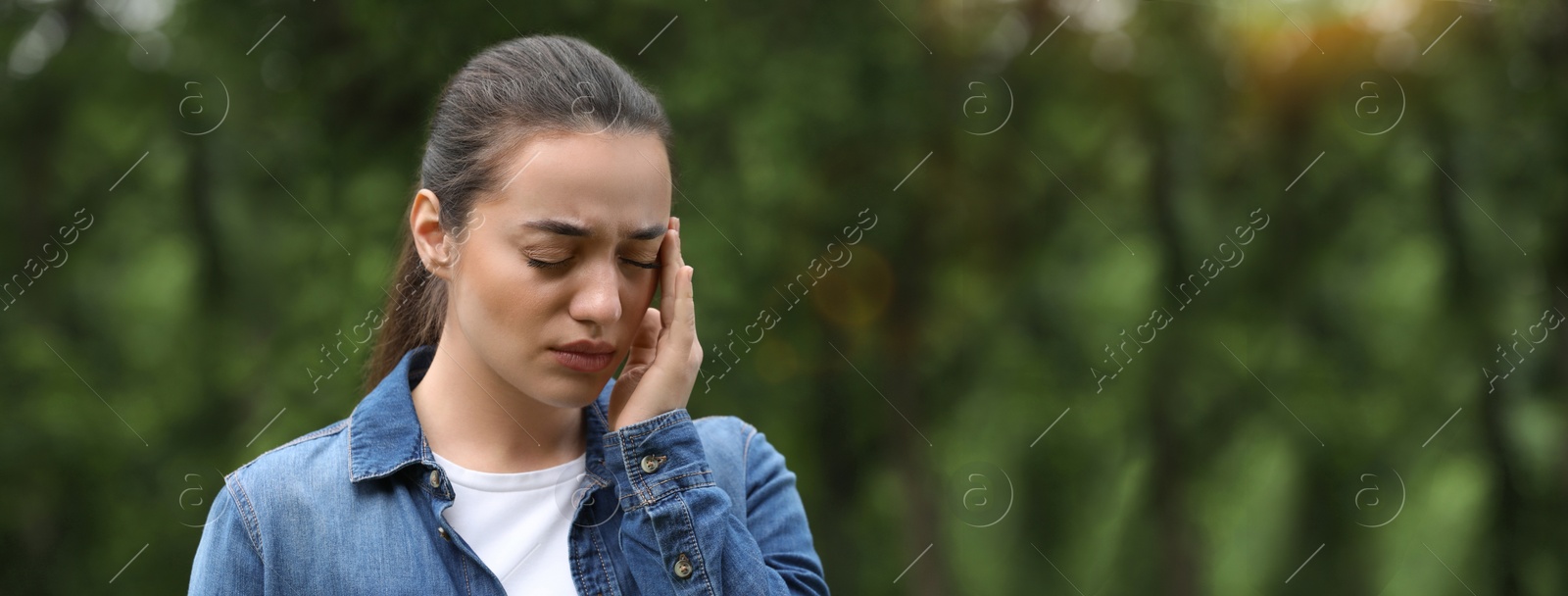 Image of Woman suffering from seasonal spring allergy outdoors. Banner design with space for text