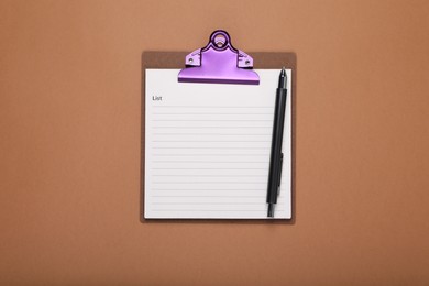 Clipboard with to do notes for daily planning and pen on brown background, top view. Space for text