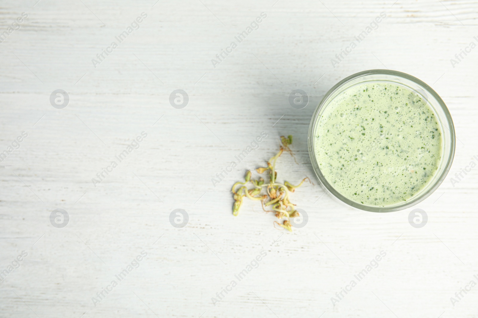 Photo of Green buckwheat smoothie on white wooden table, flat lay. Space for text