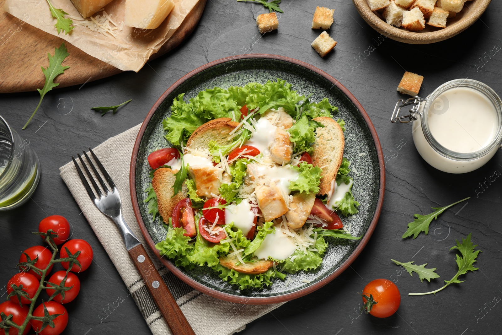 Photo of Delicious fresh Caesar salad on black table, flat lay