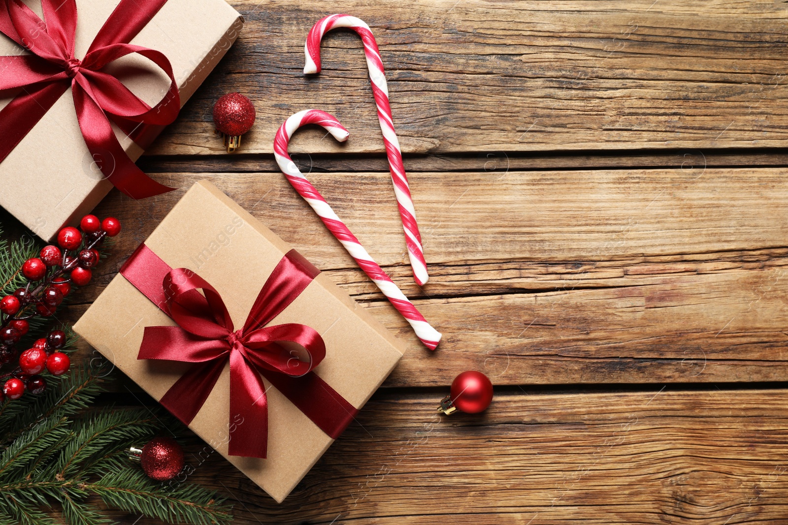 Photo of Gift boxes, candy canes and Christmas decor on wooden table, flat lay. Space for text