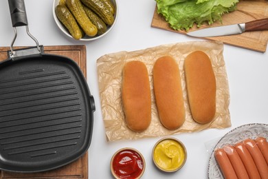 Photo of Different tasty ingredients for hot dog and grill pan on white table, flat lay