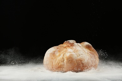 Photo of Loaf of bread on table against dark background. Space for text