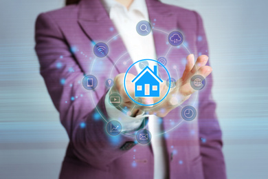 Image of Home security concept. Woman demonstrating digital house on grey background, closeup