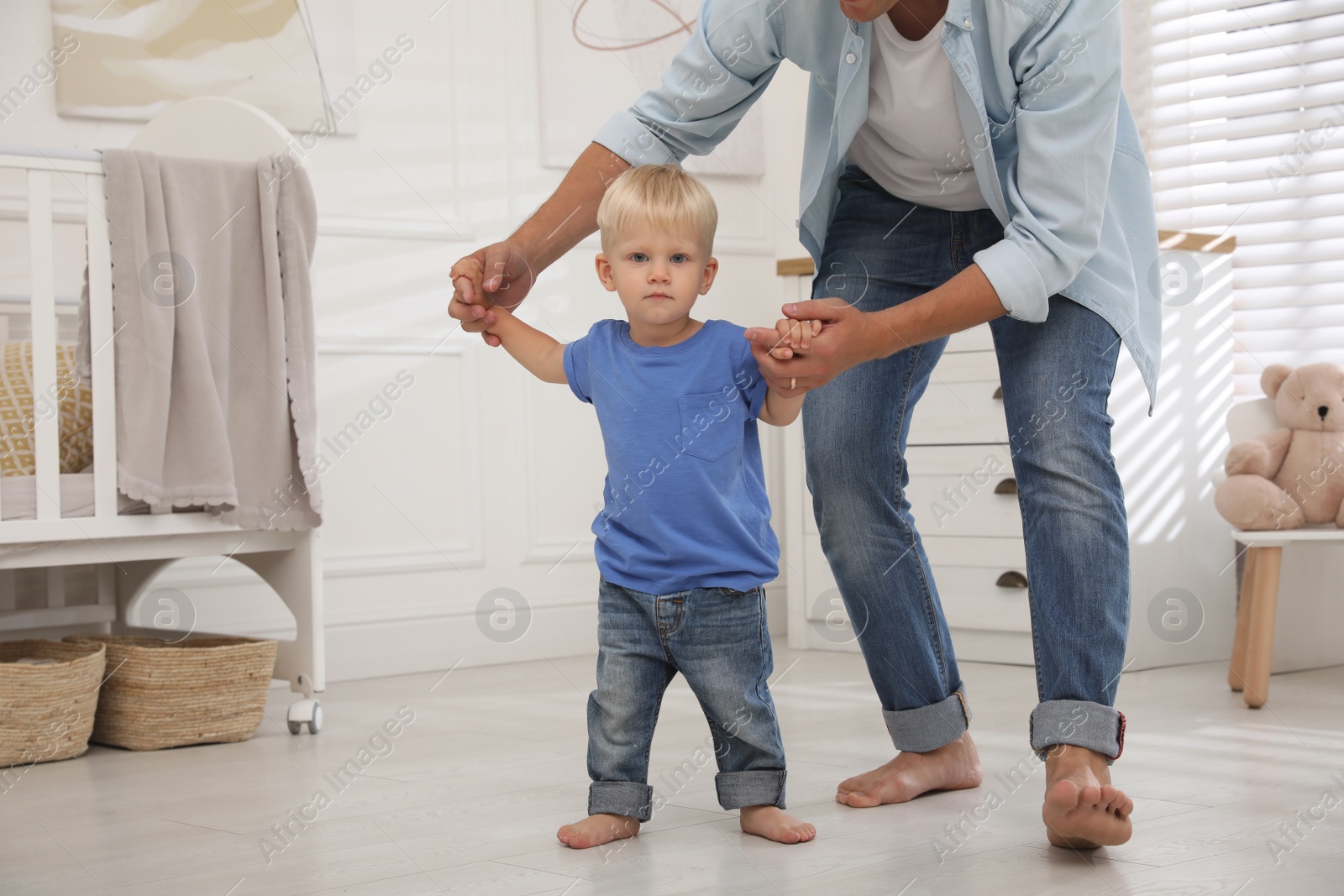 Photo of Little boy walking with father's help in nursery