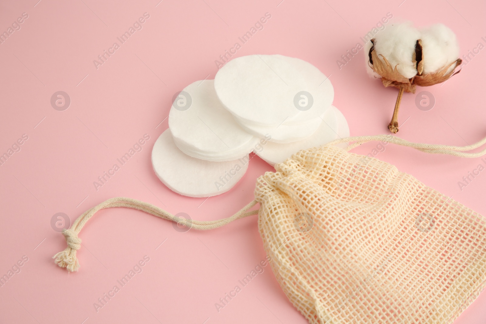 Photo of Bag, cotton pads and flower on pink background, closeup