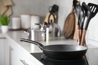 Frying pan and cooking utensils in kitchen, space for text