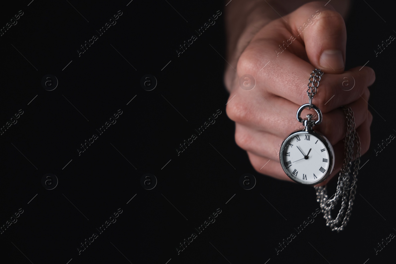 Photo of Man holding chain with elegant pocket watch on black background, closeup. Space for text
